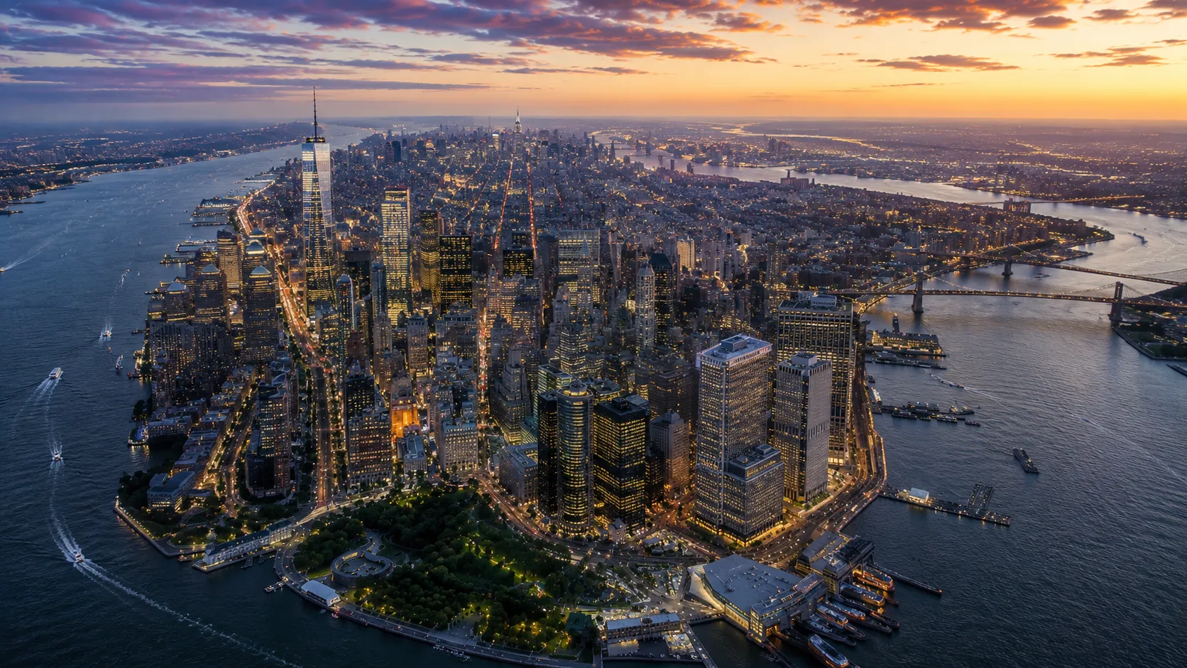 An aerial view of Lower Manhattan at dusk, with the city lit up across the skyline